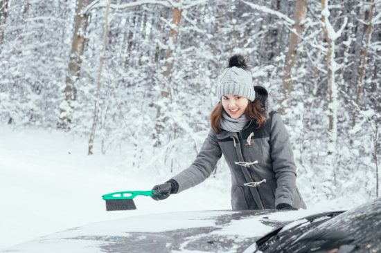 車の雪下ろしをする女性