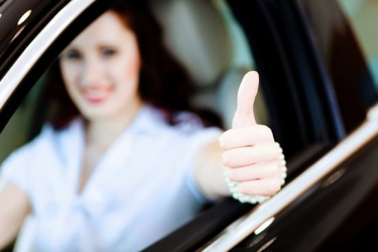 車に乗って親指を立てる女性