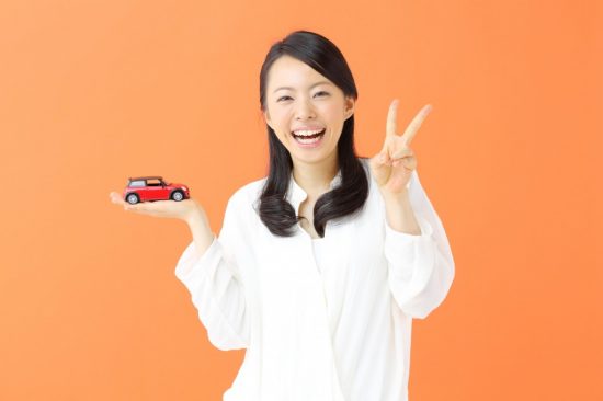 片手にオモチャの車を乗せてピースする女性