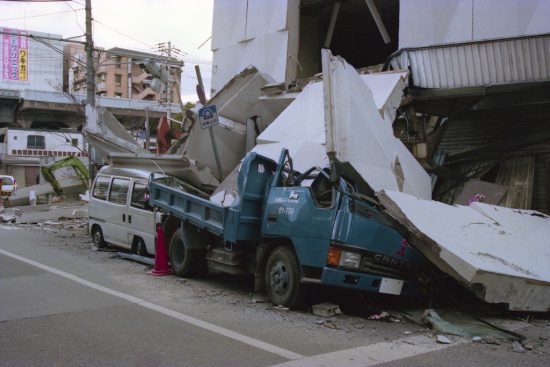 地震で倒壊したビルの下敷きになっている車