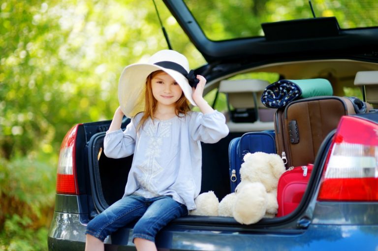 車のトランクに座る少女と積載された物