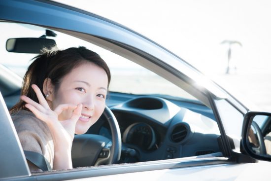 車に乗ってOKサインを出す女性