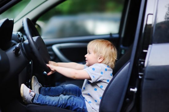 車の運転席に座る子供